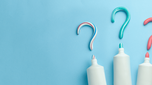 Colorful toothpaste swirls shaped like question marks alongside toothpaste tubes on a blue background.